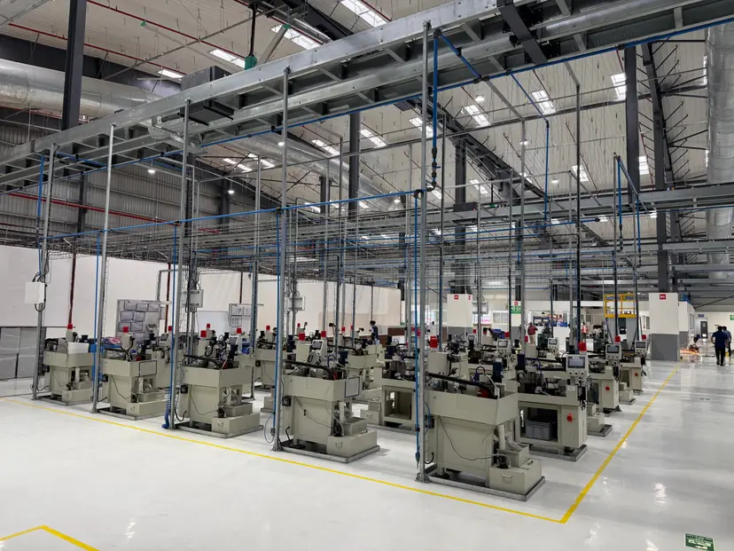 Rows of CNC machines on a finished production floor with overhead power and utility drop lines