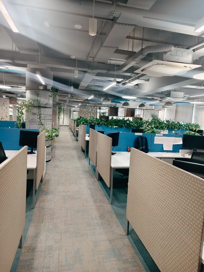 Open-plan office workstation fit-out with acoustic desk dividers, planters and false ceiling AC diffusers